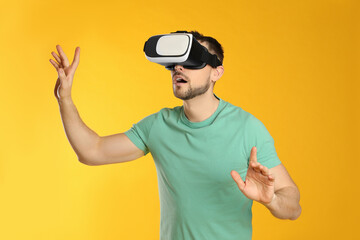 Naklejka premium Man using virtual reality headset on yellow background