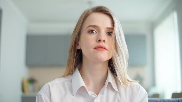 POV of beautiful young woman in white short nodding head and smiling at camera during video conference. Businesswoman expressing agreement during video call or online job interview from home