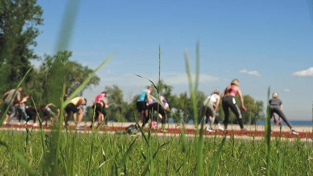 group fitness workout outdoors. fitness outdoors. group of people, wearing activewear, is exercising together, on sports ground, on the beach, city park. view from the back. blurred focus. healthy