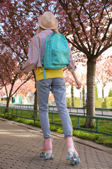 Obraz premium Young woman roller skating in spring park, back view