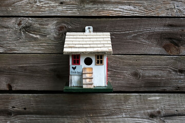 Closeup of a small wooden bird house on a wooden wall.