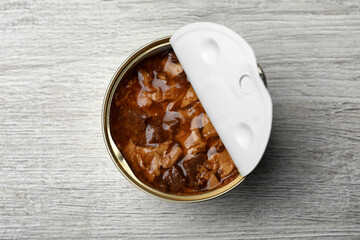 Tin can of wet pet food on white wooden table, top view
