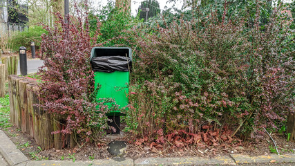 Trash can in the bushes.