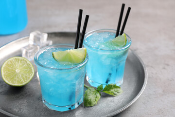 Tasty fresh light blue drink with lime on grey table