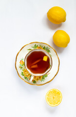 Cup of tea with cut lemon in it, whole lemons on the white background