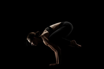 Obraz na płótnie Canvas cute caucasian girl exercising yoga poses against dark backgroung. side lit silhouette.
