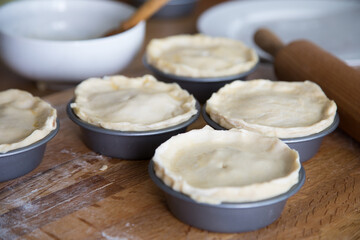 Preparing meat pies in baking tins with pastry shell 