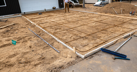 Wood frame and reinforcing steel rods or rebar used in preparation for concrete driveway at a construction job site.