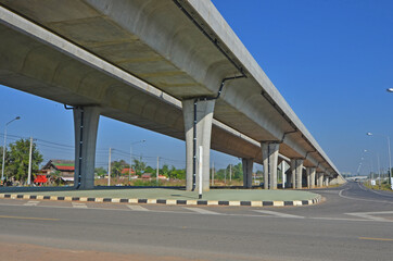 Asphalt road and traffic island under high concrete bridge