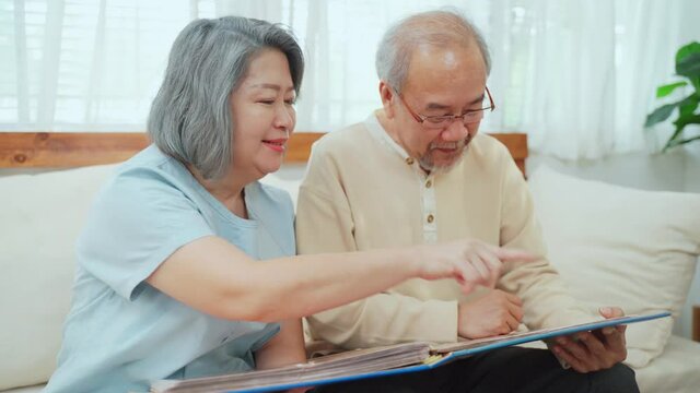 Senior couple looking photo album, photo book together in living room.