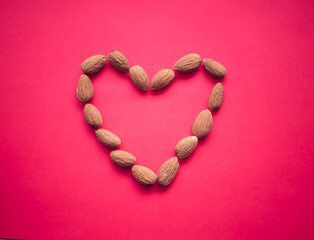 Obraz premium Heart shaped almonds on a soft pink background, heart health, Valentine's Day 