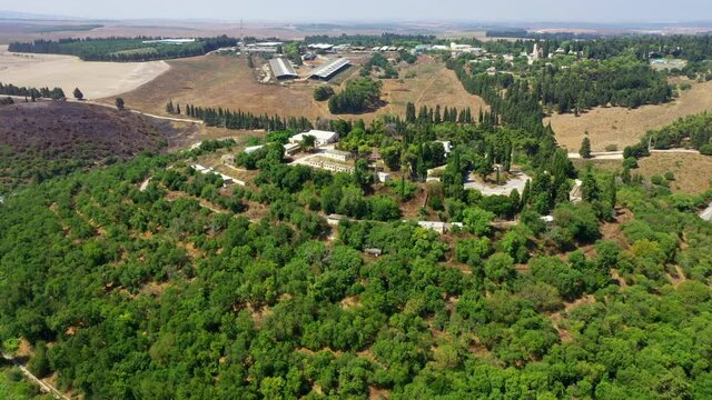 Aerial Shot Of Buildings And Trees At Kibbutz, Drone Flying Forward Over Landscape - Megiddo, Israel