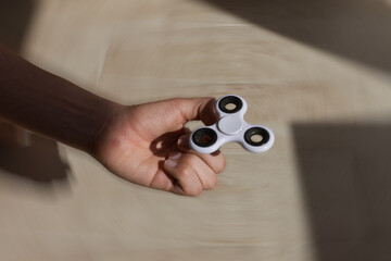 Closeup of a hand holding a fidget spinner on a blurry floor background