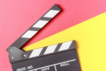 Fototapeta na wymiar The clapperboard on yellow and red background close-up top view.