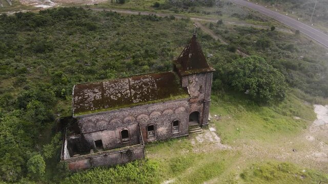 Aerial drone footage few meters above and old church from french colonial era in Indochina. Camera is moving around the architecture in a green landscape and we can see clouds and fog around. Cambodia