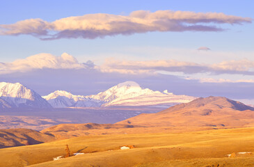 Fototapeta na wymiar Kurai steppe in the Altai Mountains. Snow-capped peaks of the North Chui range in the morning light in spring under a blue sky. Siberia, Russia