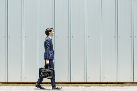 歩く若いビジネスマン（通勤・外回り）・コピースペースのある画像