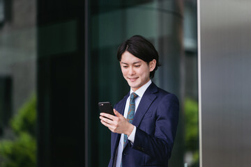 Fototapeta na wymiar 出社する若い男性・スマートフォンでIoT・ビジネスイメージ