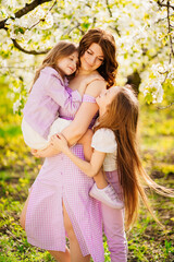 Happy mom and two daughters in a blossoming spring garden. parental love.