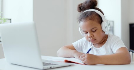 Naklejka premium Afro american kid girl school pupil wearing headphones studying online from home watching web class lesson or listening tutor by video call elearning on pandemic isolation. Children remote education.