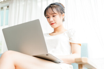 portrait of young girl sitting on sofa at home using laptop