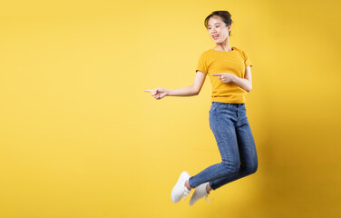 Fototapeta na wymiar Full length portrait of cheerful girl jumping up isolated on yellow background