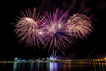 bright beautiful multi-colored fireworks flowers bloom over the river during the holiday