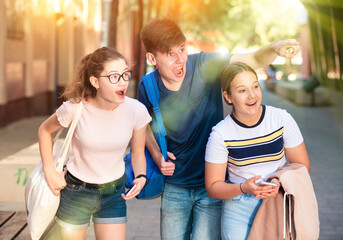 Surprised teenager points out something interesting to two girlfriends