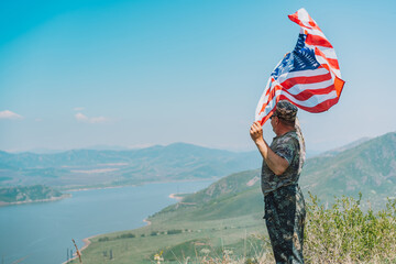 Man in military uniform holding american flag in front of nature