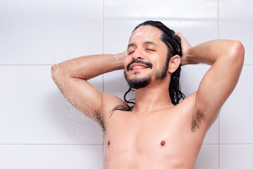 Young latin man with eyes closed with smily face taking a shower in the morning