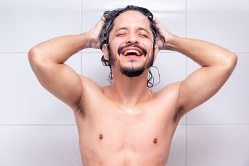 Young latin man smiling in the shower washing his hair
