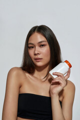 Portrait of young asian girl holding container with pills