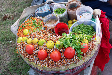 Chola chaat and chana mixture, a popular street food in India, consists of chana, tomato, carrot, coriander leaves, chutney, chilli, lemon and chaat masala displayed in a food stall for sale