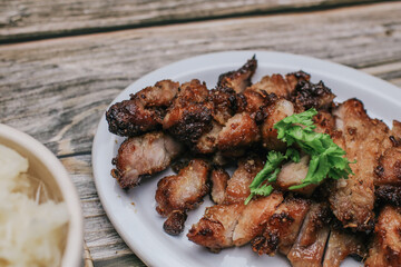 Grilled Pork Neck with Spicy sauce and steamed sticky rice on rustic wooden table, Thai Food.