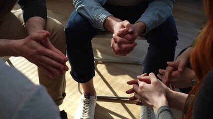 Close-up hands of unrecognizable multiethnic diverse men and women sitting in circle during group interpersonal therapy session. Tracking shot of people telling about his mental problem or addiction.