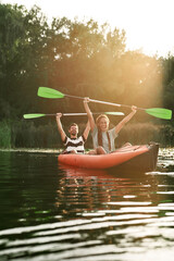 Couple of excited friends having fun while kayaking in a river surrounded by the beautiful nature...