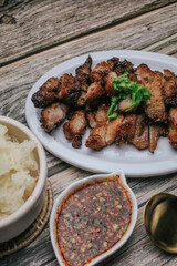 Grilled Pork Neck with Spicy sauce and steamed sticky rice on rustic wooden table, Thai Food.