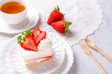 Homemade strawberry cake on a white plate with tea.