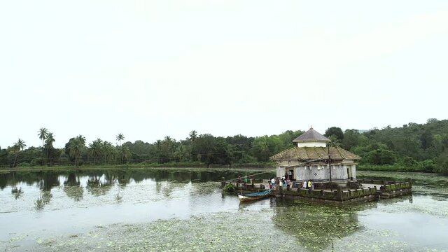 Tourist visiting old architecture on wooden platform surrounded by lake during sunny day in India.