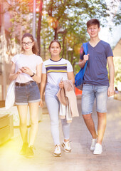 Three positive teens walk along spring street