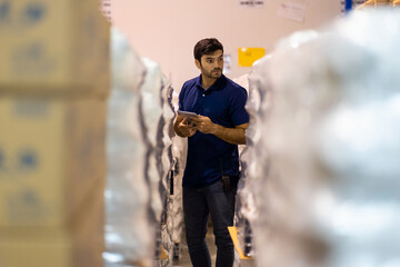 Warehouse male worker using digital tablet checking products or parcel goods in industry factory warehouse. Inspection quality control