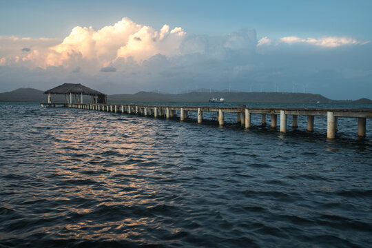 Dramatic image of sunset on the Caribbean coast, with long dock in the sea, with dramatic skies and clouds.