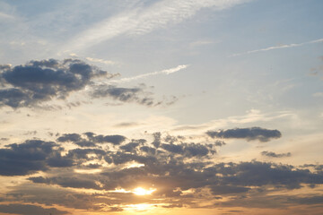 Beautiful evening blue sky at sunset with flaming bright light clouds. A warm summer evening at sunset. Bright sunset