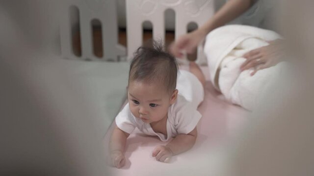 asian baby infant learning crawling skill development by mother woman encourage at home. parent mother assist helping baby crawl lesson. authentic life at home. baby infant playing in playpen. 