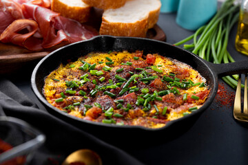 Egg omelet with sausage and seasonings in a cast iron pan close up, soft focus
