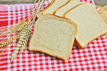 White bread toast with Wheat and red tablecloth on wooden background.