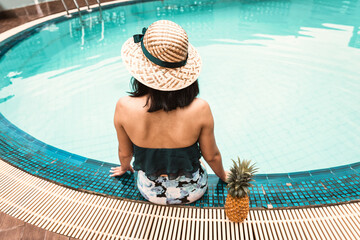 Rear View of Sexy Woman in Swimsuit Relaxing in Swimming Pool, Beautiful Woman Wearing Straw Hat...