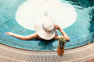 Sexy Woman in Swimsuit is Relaxing in Swimming Pool, Beautiful Woman Wearing Straw Hat and Relax...