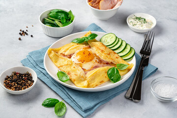 Breton crepe with ham, cheese and basil on a grey background. French breakfast.