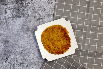 Potato pancake on a white square  plate on a dark background. Top view, flat lay